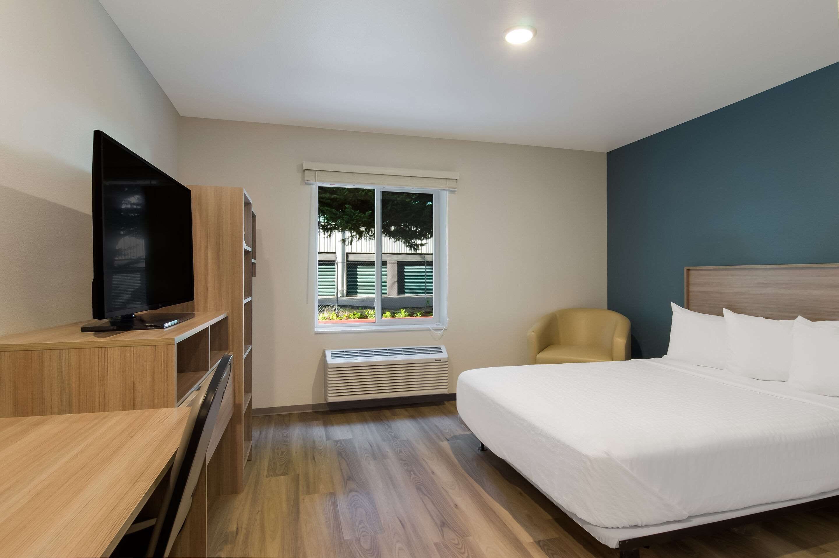 A hotel room with a bed, a TV, a desk, and a chair.