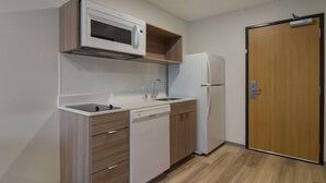 Una cocina compacta equipada con microondas, lavaplatos, fregadero y refrigerador.
