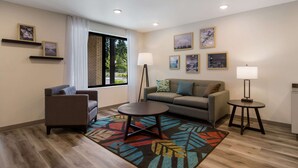 Una sala de estar moderna con un sofá, un sillón, dos mesitas auxiliares y una alfombra estampada.