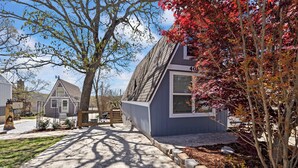 Un quartier résidentiel avec une maison portant le numéro 409, une allée et un arbre aux feuilles rouges.