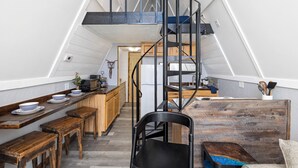 Une cuisine compacte avec des plans de travail en bois, un îlot central et une chaise noire.