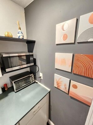 Compact kitchenette with microwave, toaster oven, and functional storage.