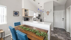 Een moderne keuken met witte kasten, een houten eiland en een eetgedeelte met blauwe stoelen.