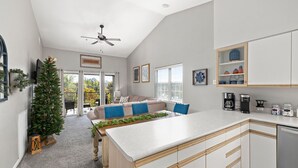 Een moderne keuken met een centraal eiland, witte kastjes en een plafondventilator.
