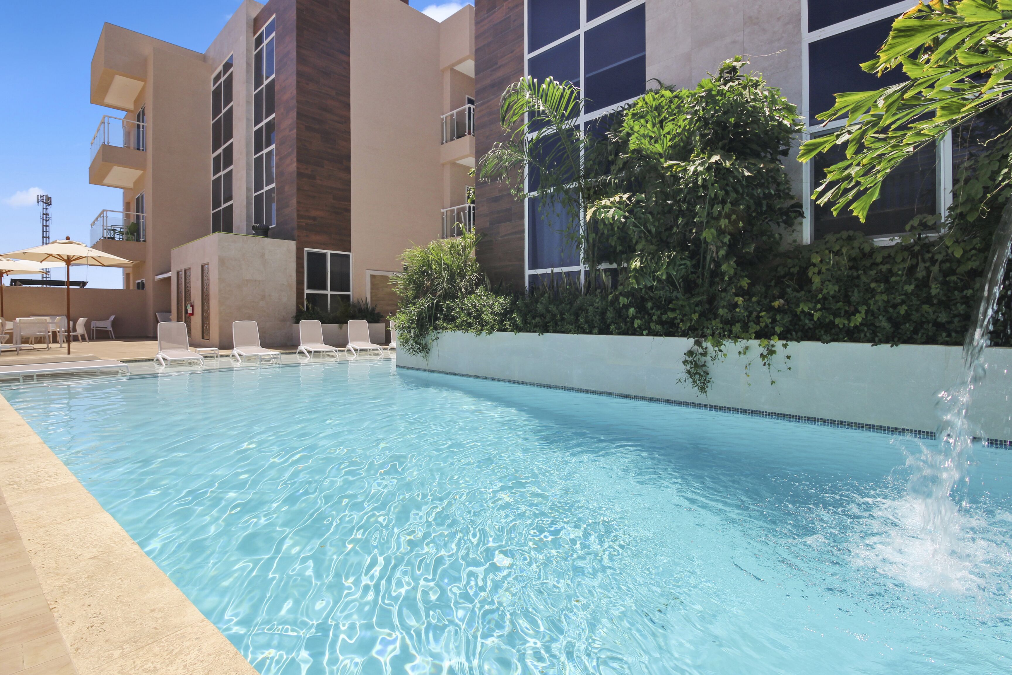 A swimming pool with lounge chairs and a waterfall feature.