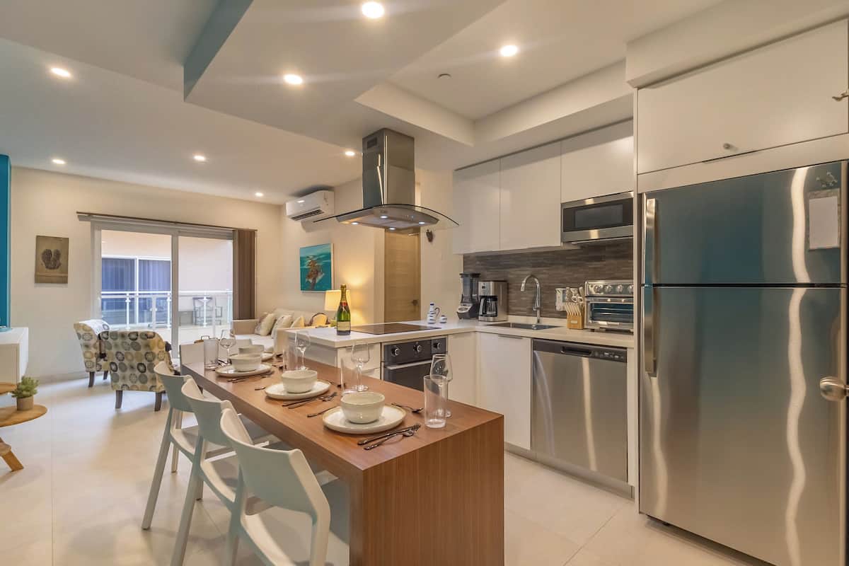 A modern kitchen with stainless steel appliances, a central island with seating, and a dining area with a view.