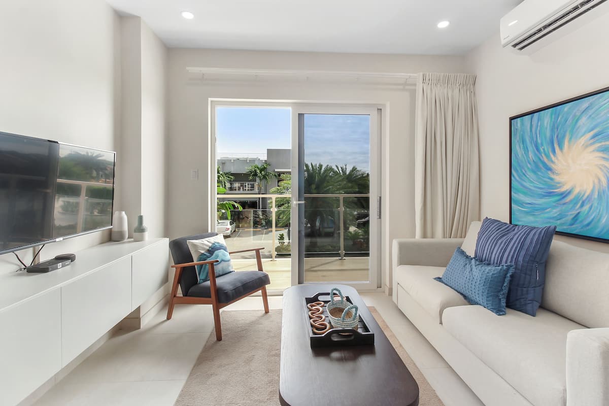 A modern living room with a flat-screen TV, a sofa, a chair, and a coffee table.
