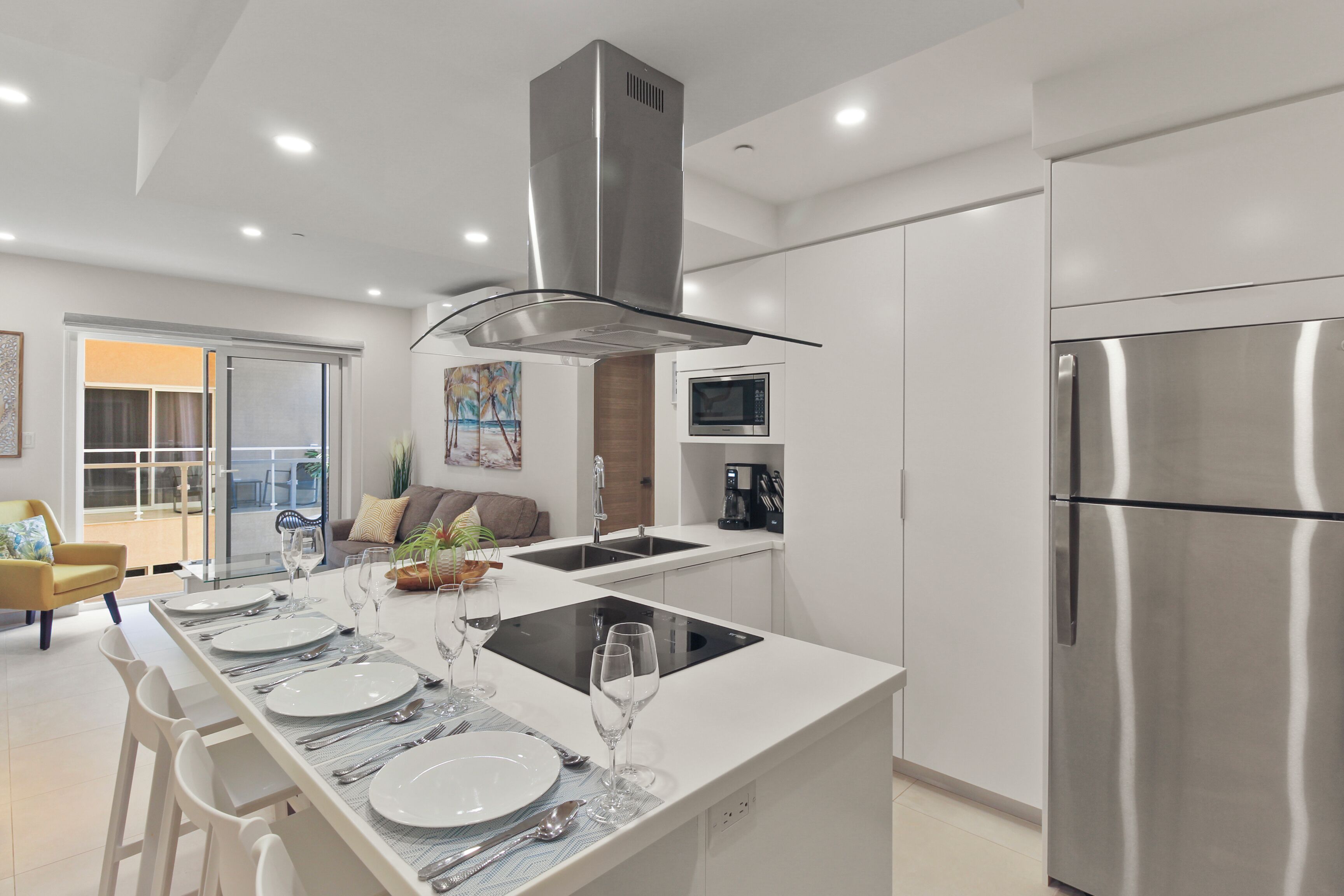 Una cocina moderna con armarios blancos, electrodomésticos de acero inoxidable y una isla central con estufa integrada.