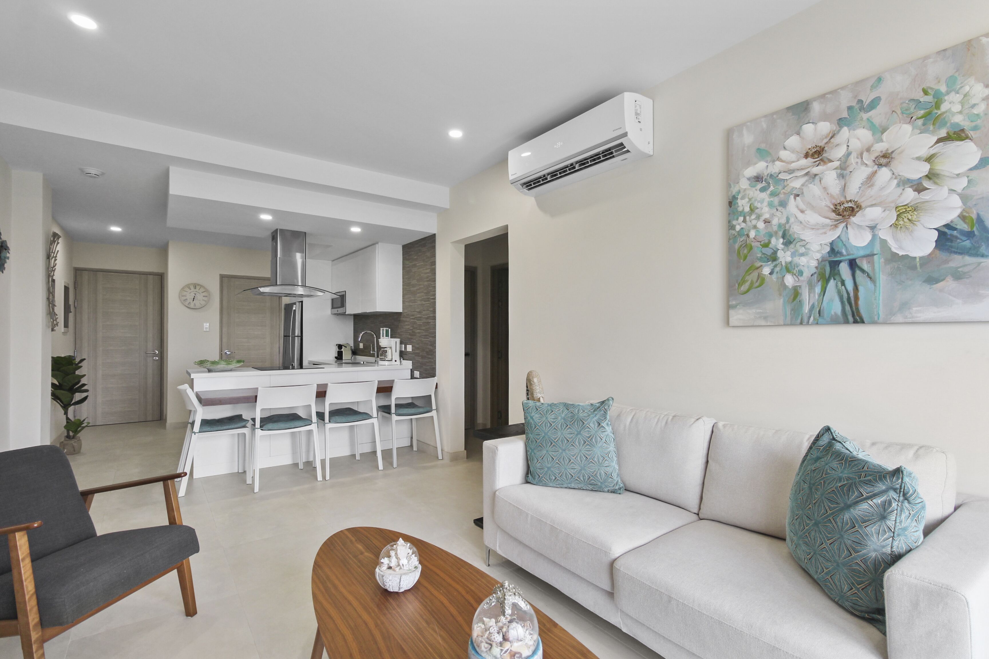 A modern living room with a sofa, a coffee table, and a dining area with a white table and chairs.
