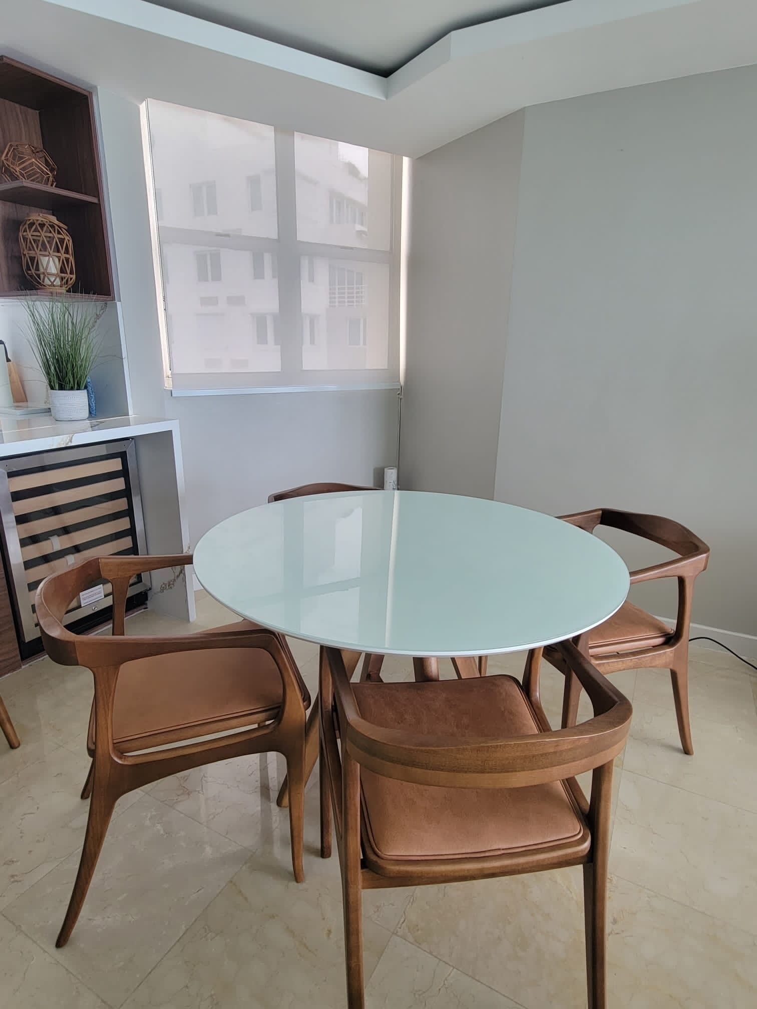 A dining area with a round glass table and six brown chairs.