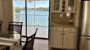 A kitchen with a view of a lake, a dining area with wicker chairs, and a refrigerator. - Dock Beach House in Sombrero Beach (Marathon)
