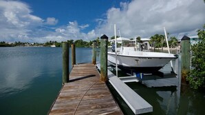 A boat docked at a wooden pier with a clear sky and calm water. - Dock Beach House in Sombrero Beach (Marathon)