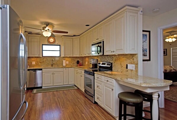 Kitchen features stainless steel appliances, a sink, and a stove, set against a wooden floor.