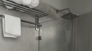 Un baño con inodoro, cabina de ducha y toallero con toallas.