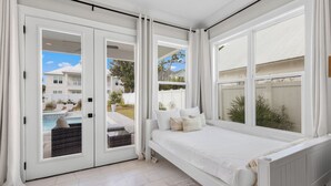 A bedroom with a large window, a bed, and a view of a swimming pool and neighboring houses. - Seagrove Beach - Private Pool + Spa - Bikes (Seagrove)
