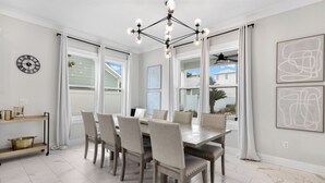 A dining area with a wooden table and chairs, a chandelier, and artwork on the walls.