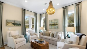 A spacious living room with a large sofa, two armchairs, a coffee table, and a chandelier.