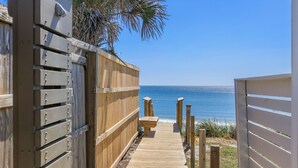 A wooden deck leading to a beach with a view of the ocean.