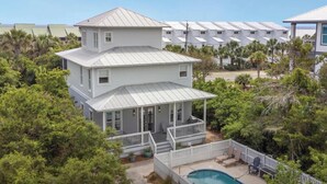 A two-story house with a balcony, surrounded by trees and a swimming pool.