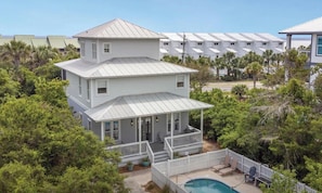 A two-story house with a balcony, surrounded by trees and a pool.