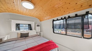 Una camera da letto con un letto, una finestra vista, un ventilatore a soffitto e una parete bianca.