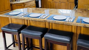 Una cucina con mobili in legno, piani in granito e sgabelli da bar.