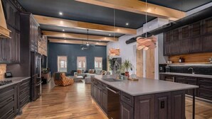 A spacious kitchen with dark wood cabinets, a large island, and a modern pendant light. - Luxury Loft Overlooking Downtown (Lincolnton)