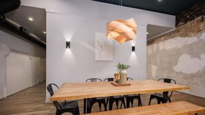 A modern conference room with a wooden table, black chairs, a bench, a hanging light fixture, and a wall-mounted artwork. - Luxury Loft Overlooking Downtown (Lincolnton)