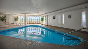 An indoor swimming pool with clear glass walls, lounge chairs, and a view of the sky. - Seawatch Oceanview Unit 502 (Old Orchard Beach)