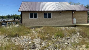 A single-story house with a metal roof, two windows, and a small porch. - Acadia Birds Eye View Cottage (Southwest Harbor)