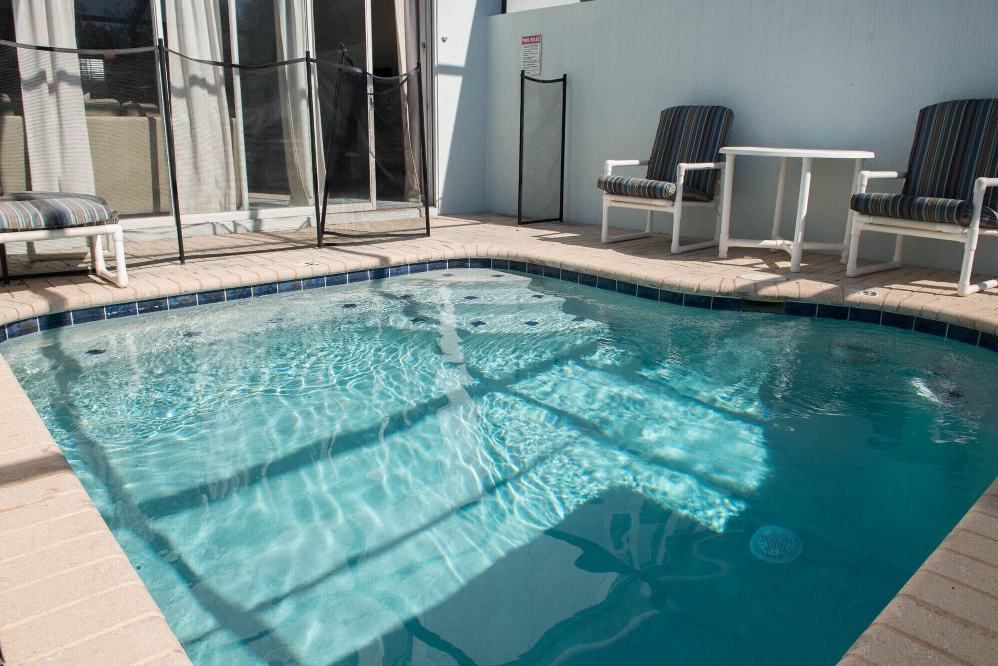 A swimming pool with clear water, surrounded by lounge chairs and a covered seating area.