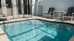 Une piscine à l’eau claire, entourée de chaises longues et d’un espace de détente abrité.