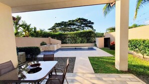Un espace extérieur aménagé avec une terrasse, une table et des chaises, une piscine et une pelouse bien entretenue.