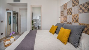 Een slaapkamer met een bed, nachtkastje, lamp en een muur met decoratieve tegels.
