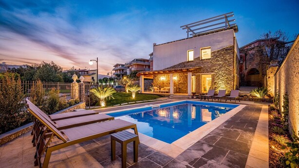 A modern pool area with a stone house, lounge chairs, and a well-lit patio. - Villa Gallus 6, Emma Villas (Taormina)