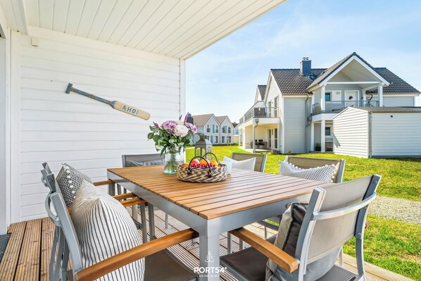 A covered patio with a wooden table, chairs, and a baseball bat leaning against the wall.