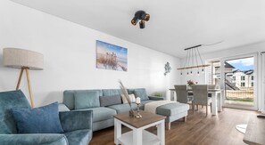 Uma sala de estar moderna com sofá, mesa de centro e área de jantar.