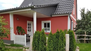 A red house with a white porch, a small window, and a white fence.