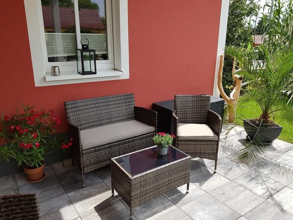 An outdoor seating area with wicker furniture, a glass-top table, and potted plants. - Vacation apartment for up to 5 people in beautiful Lusatia (Panschwitz-Kuckau OT Lehndorf)