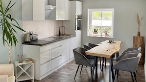 A modern kitchen with white cabinets, a wooden dining table, and grey chairs.