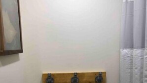 A bathroom with a wooden shelf mounted on the wall, a framed picture above it, and a shower curtain. - Riverside State Park Studio Bear Apartment+Loft (Nine Mile Falls)