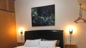 A bedroom with a bed, a painting on the wall, and two bedside lamps. - Riverside State Park Studio Bear Apartment+Loft (Nine Mile Falls)