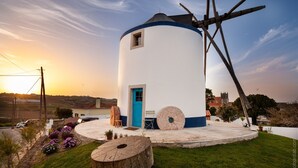 Een wit gebouw met een blauwe deur en een windmolen.