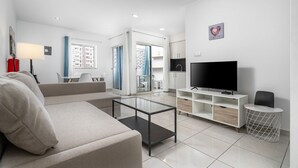 Ein modernes Wohnzimmer mit einer Couch, einem Fernseher und einem Glastisch.