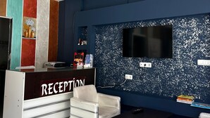 Zona de recepción con televisor, escritorio y silla.