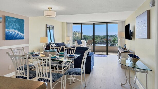 Un vaste espace de vie avec balcon, un ensemble de meubles de salle à manger et un grand tableau représentant une vague.