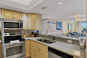 A modern kitchen with stainless steel appliances, beige cabinetry, a double sink, and a dishwasher.