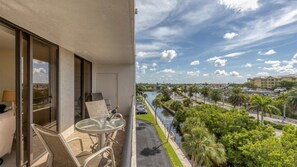 Ein Balkon mit Tisch und Stühlen, mit Blick auf einen Kanal gesäumt von Palmen und einen Hafen.