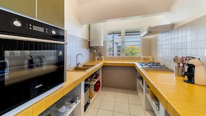 A compact kitchen with a built-in oven, a sink, and a window providing natural light. - seasonal rental for 4 people max in large independent garden level (Saint Paul)