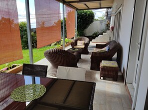 A covered patio area with wicker furniture, a small table, and potted plants. - seasonal rental for 4 people max in large independent garden level (Saint Paul)